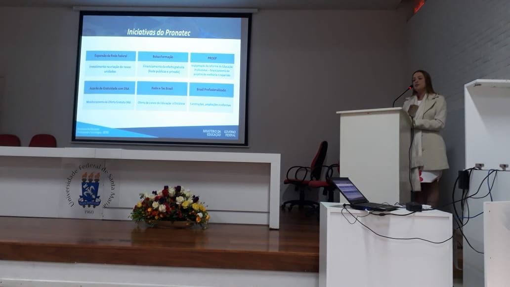 Foto horizontal colorida de uma mulher em um auditório realizando uma apresentação