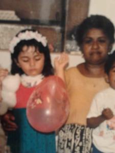 Foto colorida de uma menina à esquerda, segurando um balão, e uma senhora à direita