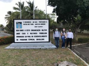 Membros da equipe Rocket Lab ao lado de placa comemorativa do Programa Espacial Brasileiro.