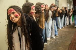 Foto colorida com uma fila de mulheres com o rosto pintado