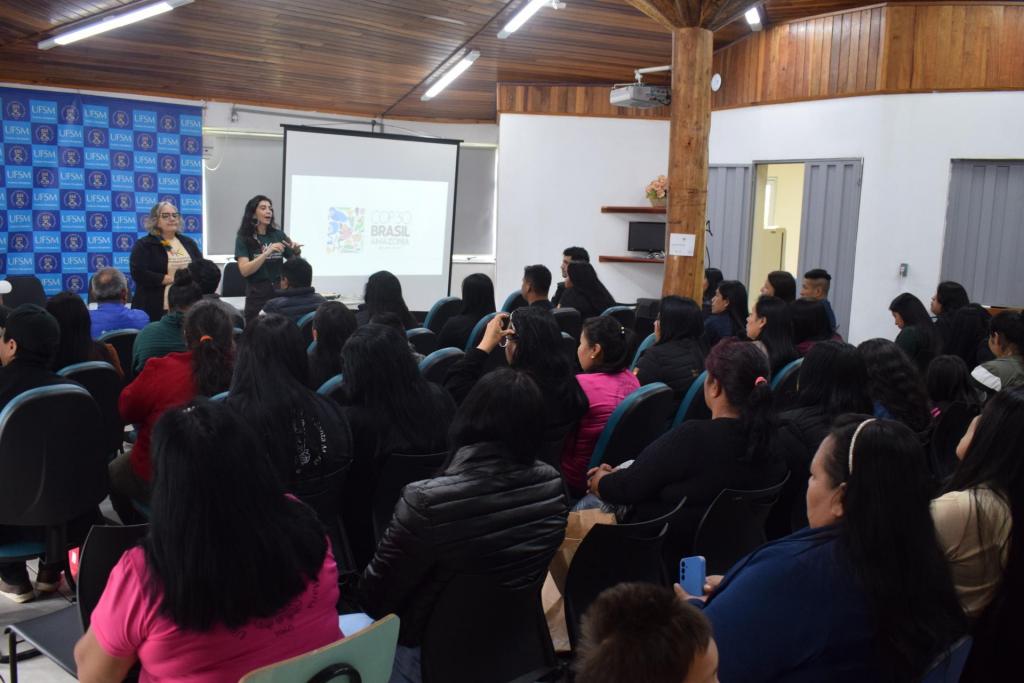 Foto colorida horizontal de duas grupo de pessoas assistindo a palestra conduzida por Eliane e Aline