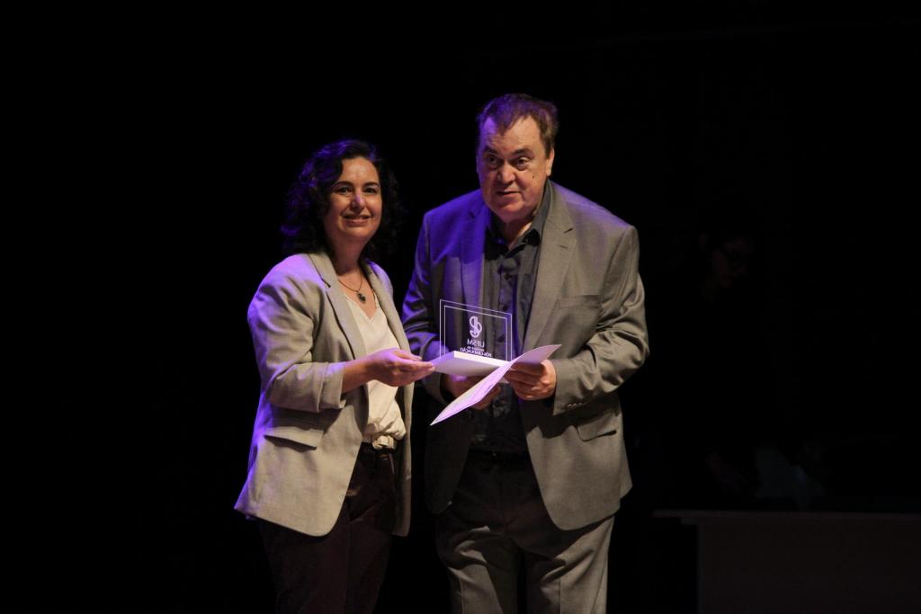 Foto colorida horizontal do destaque professor Marcos Martins recebendo prêmio