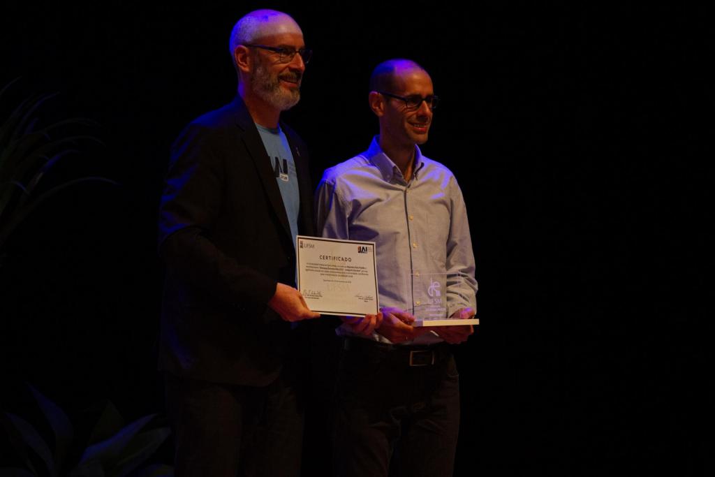 Foto colorida horizontal do professor Alejandro Ruiz Padillo recebendo o prêmio do reitor