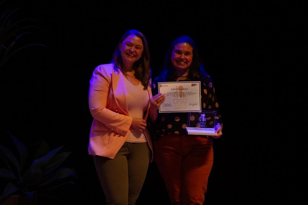 Foto colorida horizontal de Fabiana Steka recebendo prêmio