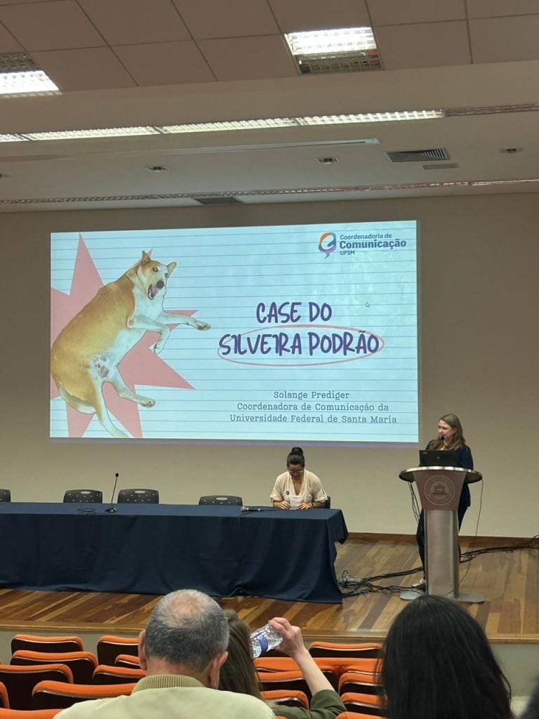 Foto horizontal e colorida de Solange Prediger apresentando um slideshow em um auditório