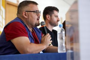 Foto horizontal e colorida de Jerônimo Tybusch segurando um microfone.