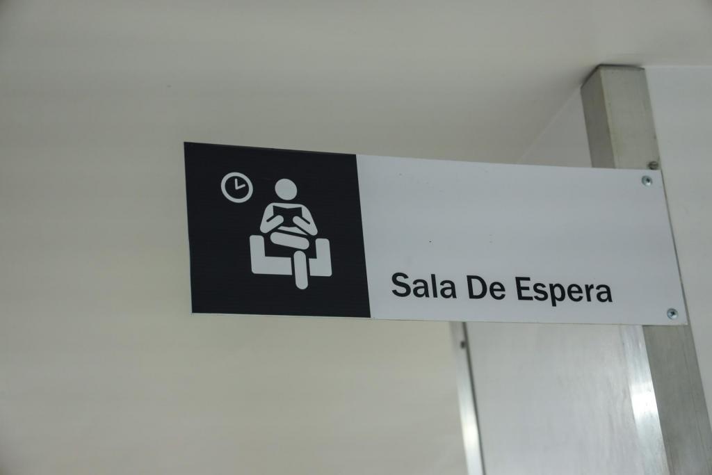 Foto colorida na horizontal com uma placa sinalizadora escrito ‘sala de espera’ localizada no Hospital Universitário de Santa Maria (HUSM)