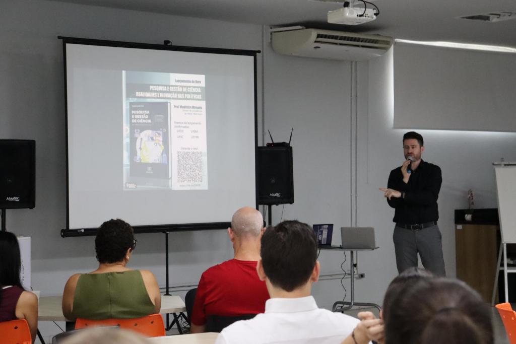 Foto horizontal e colorida de Tiago Marchesan discursando na palestra