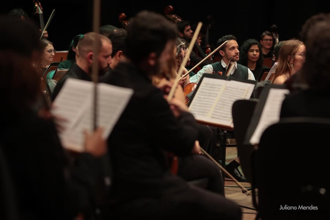 Integrantes da orquestra tocam seus instrumentos durante um concerto.