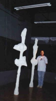 Foto vertical de duas esculturas brancas e uma pessoa