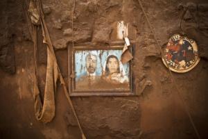 Foto de um casal pendurada em uma parede suja de barro. Ao lado, um adereço de time de futebol