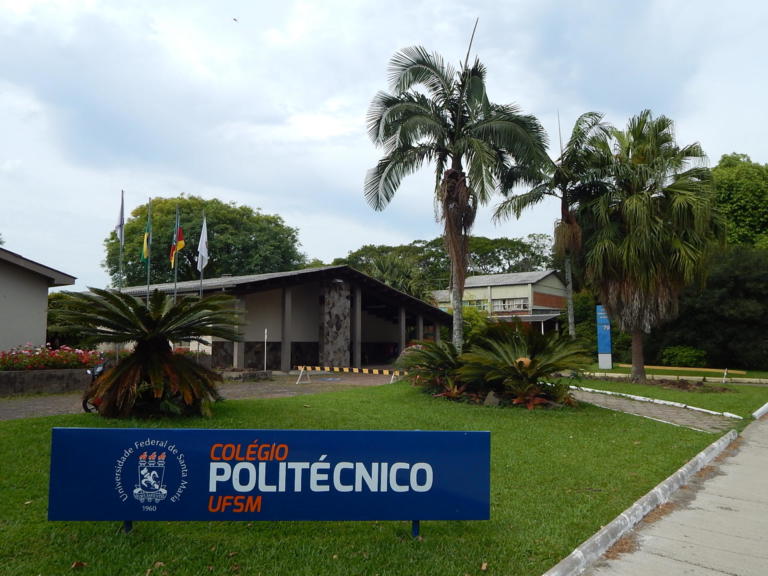 Foto prédio principal do Colégio Politécnico térreo com gramado e placa do Colégio em frente