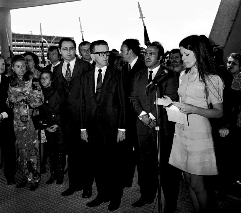 Foto preto e branca de diversas pessoas em pé em frente ao Planetário enquanto diretora lê discurso