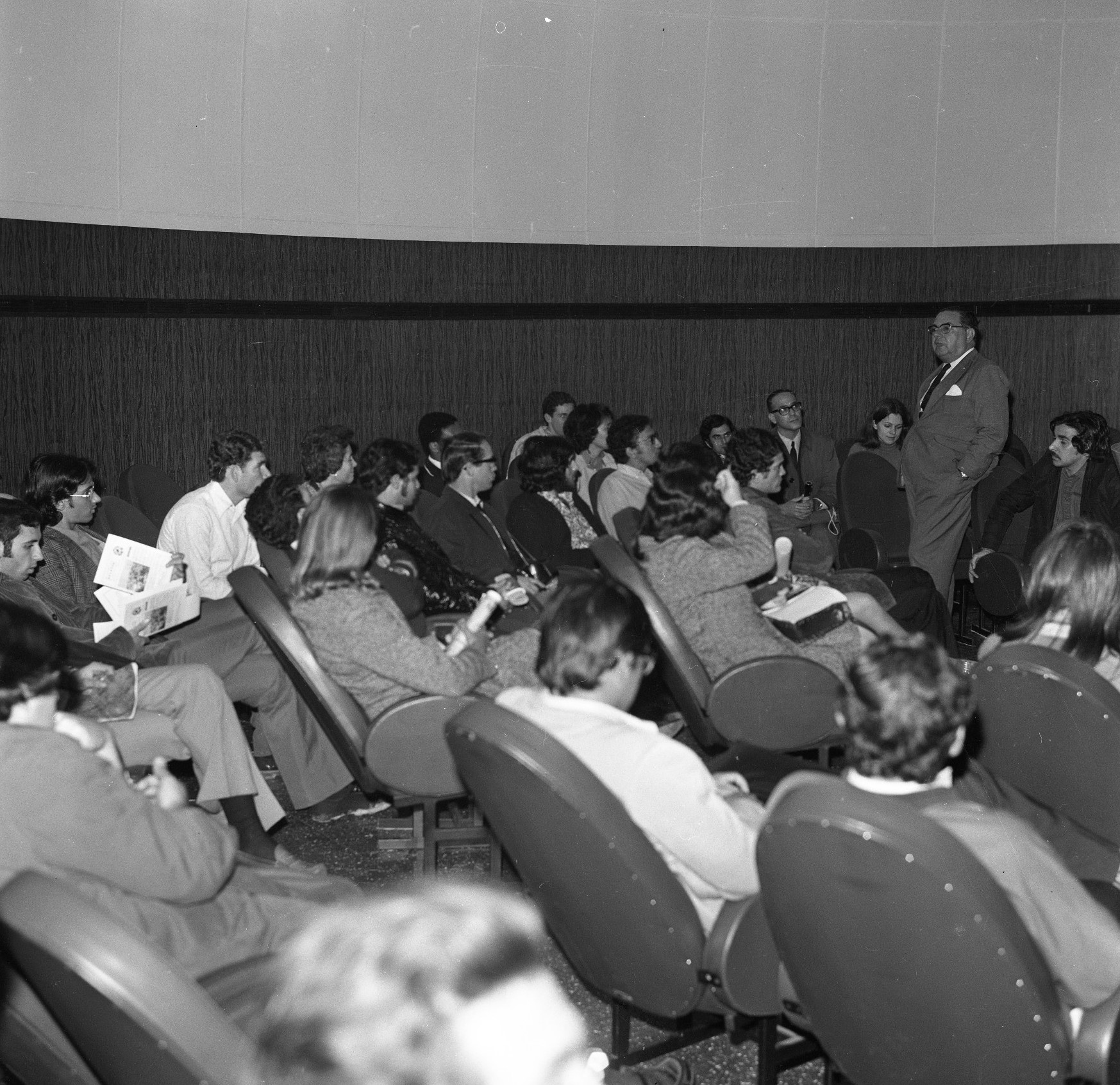 Foto preto e branca de pessoas sentadas na Sala de Projeções do Planetário