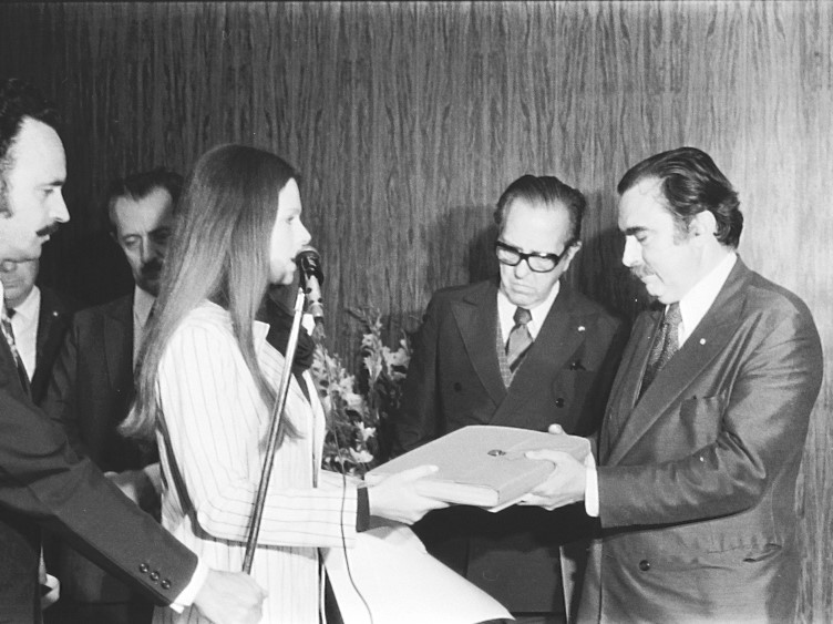 Foto preto e branca da diretora do Planetário entregando uma placa ao reitor fundador Mariano da Rocha