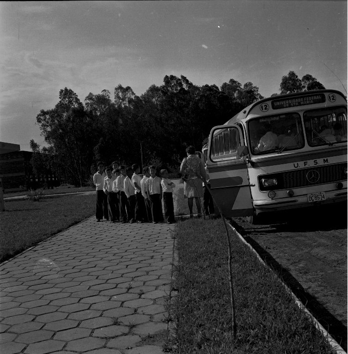 Foto preto e branca de ônibus da UFSM com diversas crianças na volta