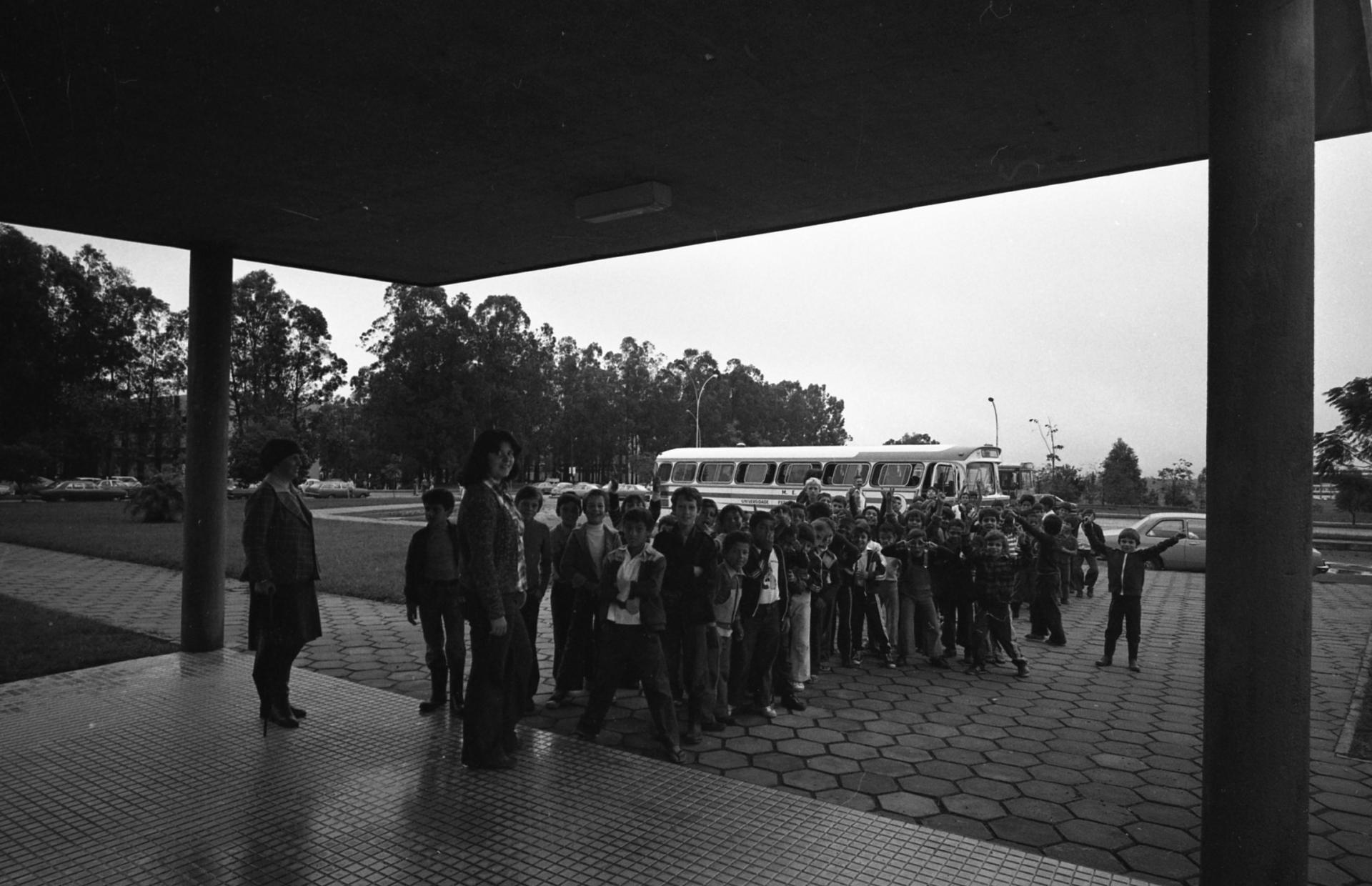 Foto preto e branca de diversas pessoas descendo de ônibus em frente ao Planetário