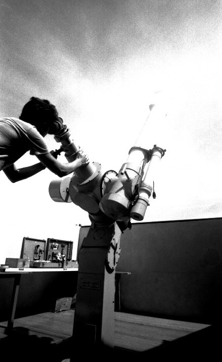 Foto preto e branca de homem operando telescópio