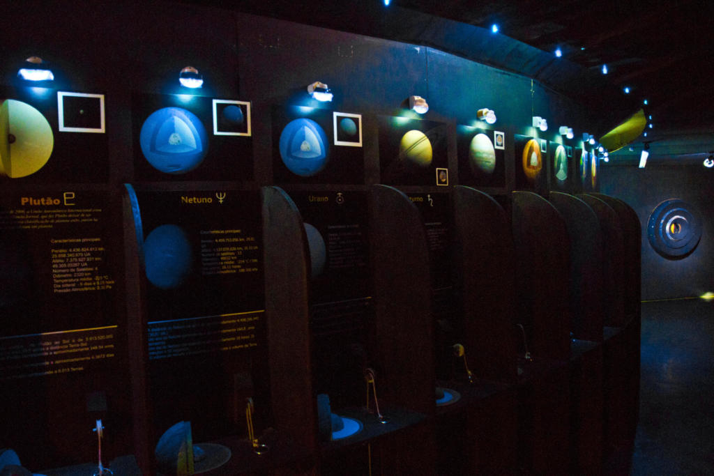 Foto do hall do Planetário no escuro com exposição de planetas iluminados