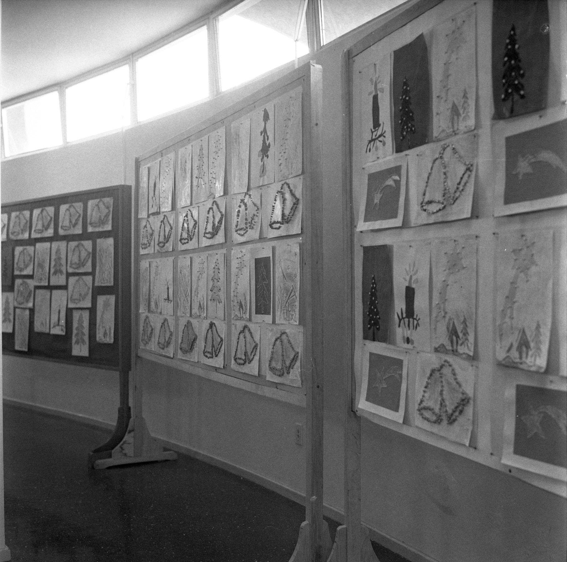 Foto preto e branca de exposição de desenhos na parede.