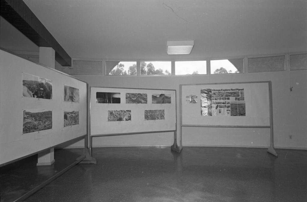 Foto preto e branca de exposição de desenhos em expositores de madeira