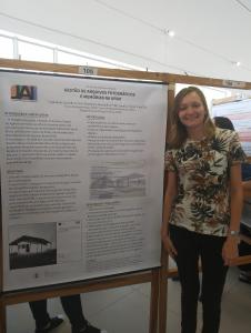 Fotografia vertical colorida de uma moça ao lado de um banner