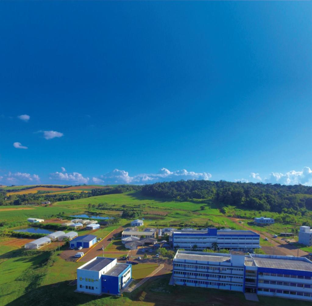 Foto aérea do campus Frederico Westphalen, campo verde, céu azul e diversos prédios