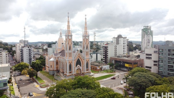 Foto aérea de praça com igreja salmão e branca no centro