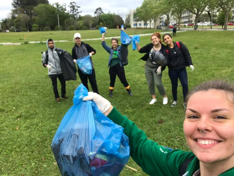 Seis alunos tirando foto com sacos de lixo na mão