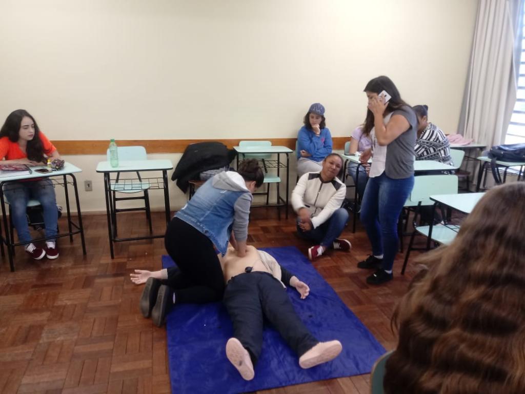 Mulher deitada no chão e outra está fazendo massagem respiratória