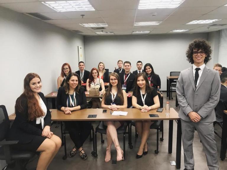 Foto de várias mulheres sentadas e um homem de terno e em pé ao lado delas.