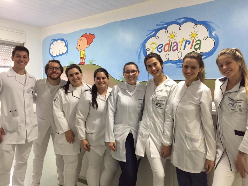 oito alunos brancos, tirando uma foto na pediatria de um hospital