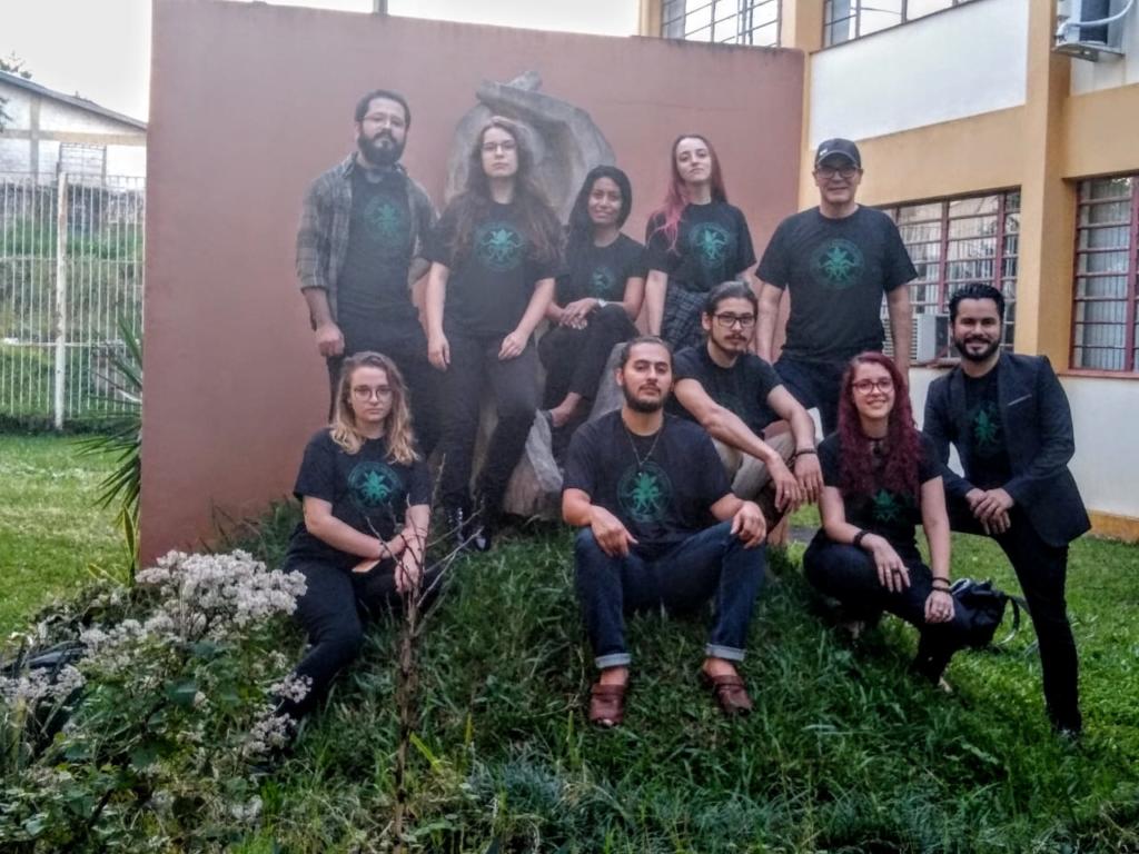Foto de dez alunos, todos vestem uma camiseta preta e estão posicionados aleatoriamente.