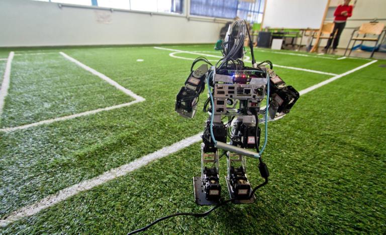 Foto de um protótipo de robô em um mini campo de futebol.