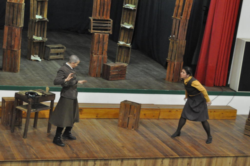 Duas pessoas fantasiadas se apresentando em palco de madeira
