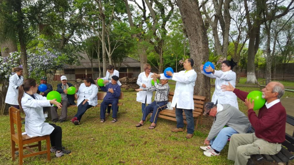 Alunos e idosos em ambiente externo fazendo atividades com balões