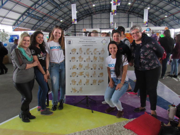 Pessoas segurando um banner com as letras do alfabeto em libras