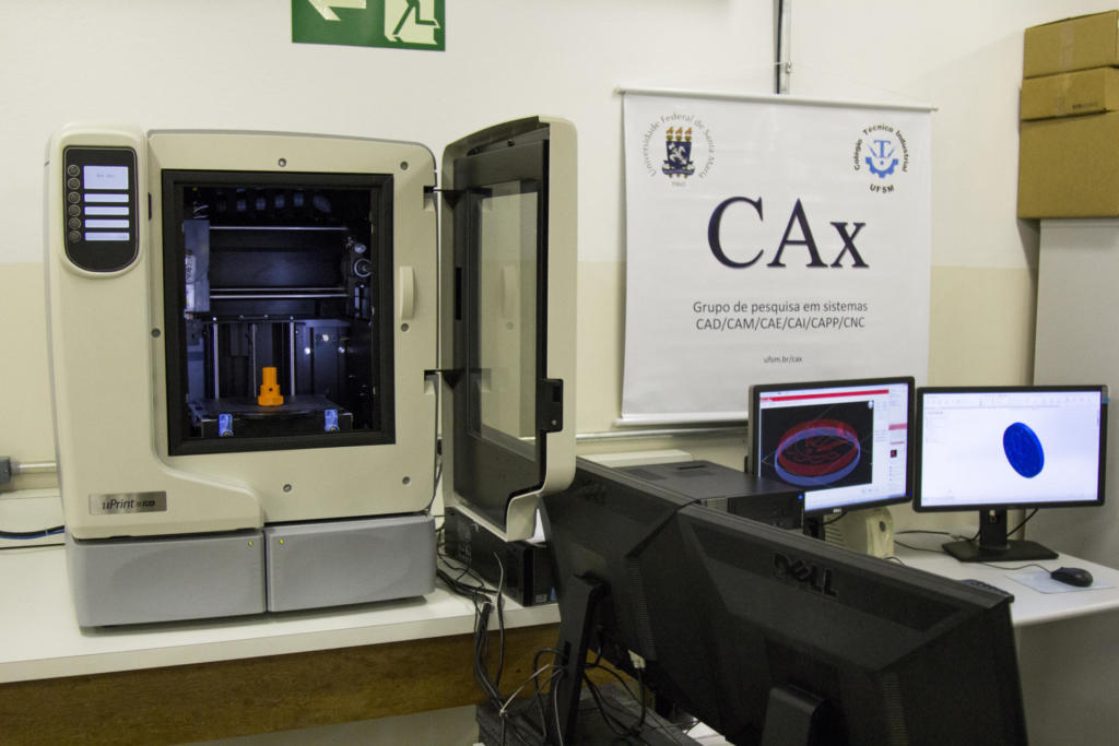 Fotografia de uma máquina e computadores usados em aula.