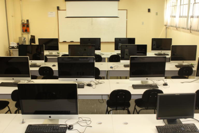 Foto de uma sala com computadores sobre a mesa.