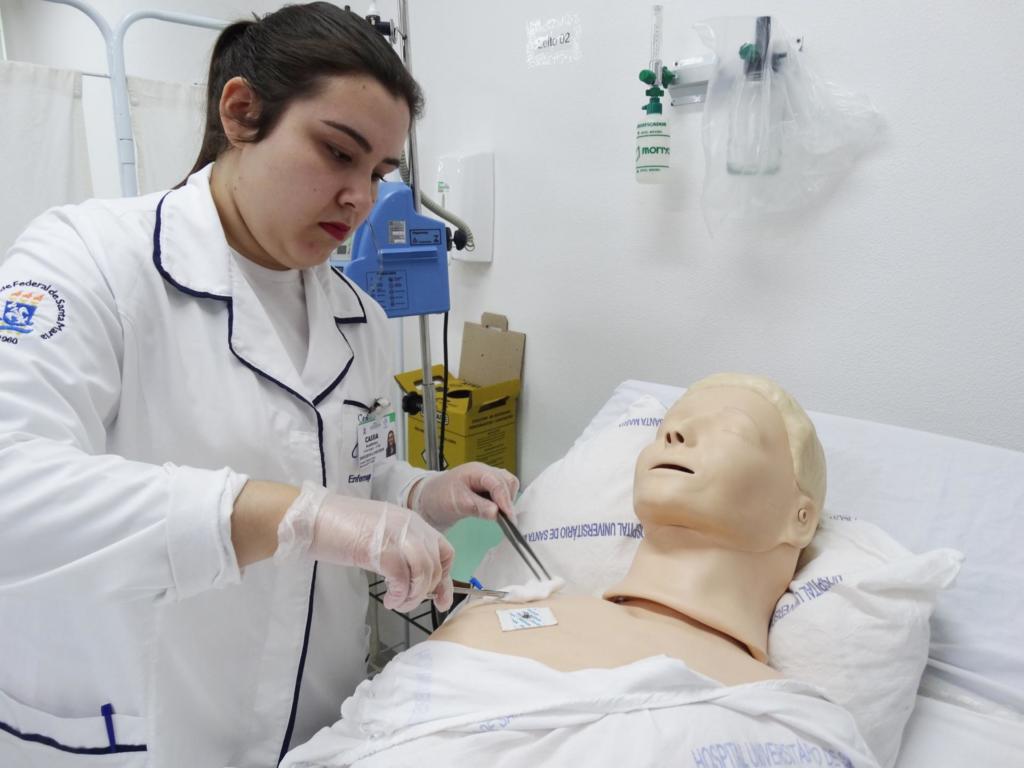Aluna branca de enfermagem, realizando procedimentos em um boneco no Laboratório de Enfermagem Santa Maria