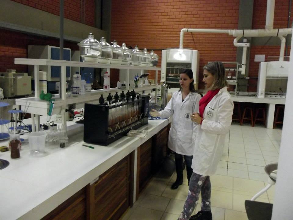 Foto de duas mulheres com jaleco branco observando uma ferramenta do laboratório.