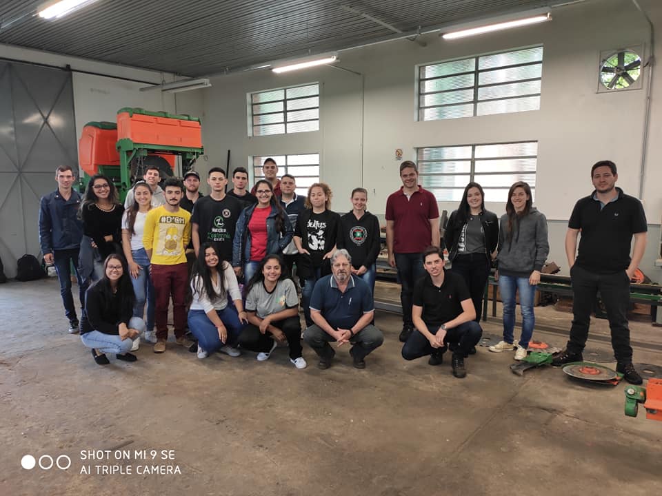 Foto de vários alunos posicionados para foto em um laboratório de pesquisa e desenvolvimento de máquinas agrícolas.