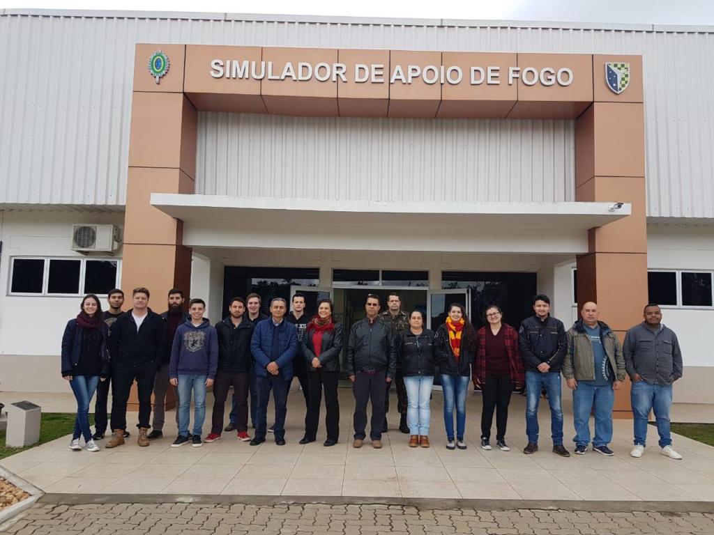 Foto de vários alunos posicionados lado a lado em frente a entrada do Simulador de Apoio de Fogo.