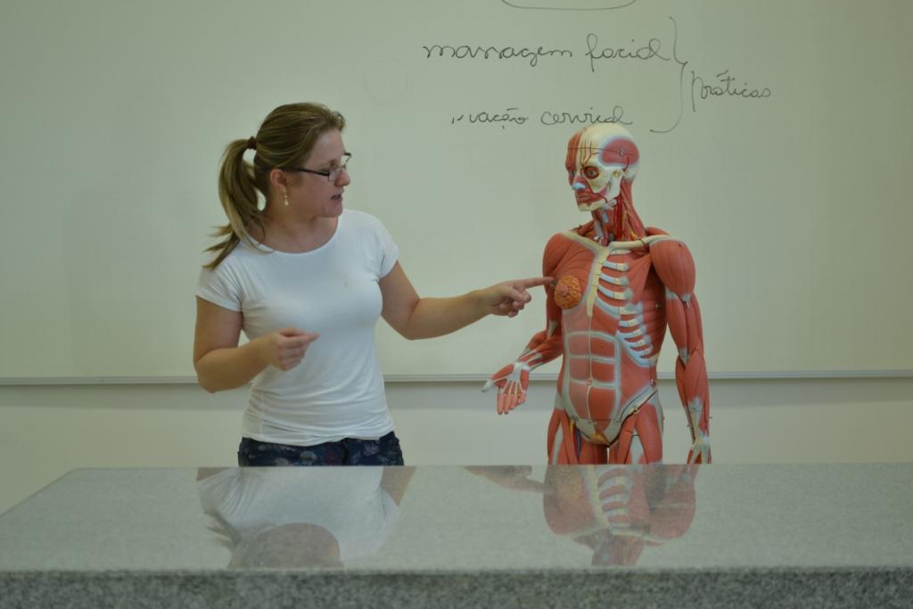 Mulher apontando para manequim do corpo humano em sala de aula