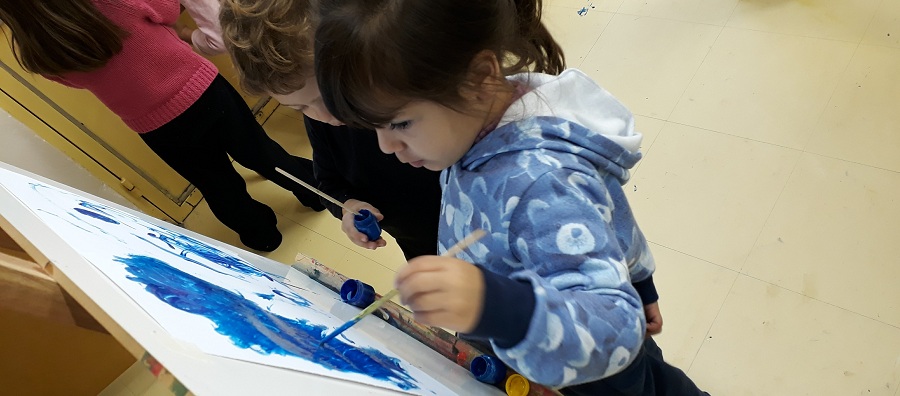 Menina pintando com pincel em tela branca