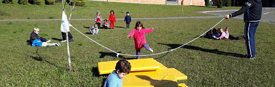 Crianças correndo e pulando corda em gramado