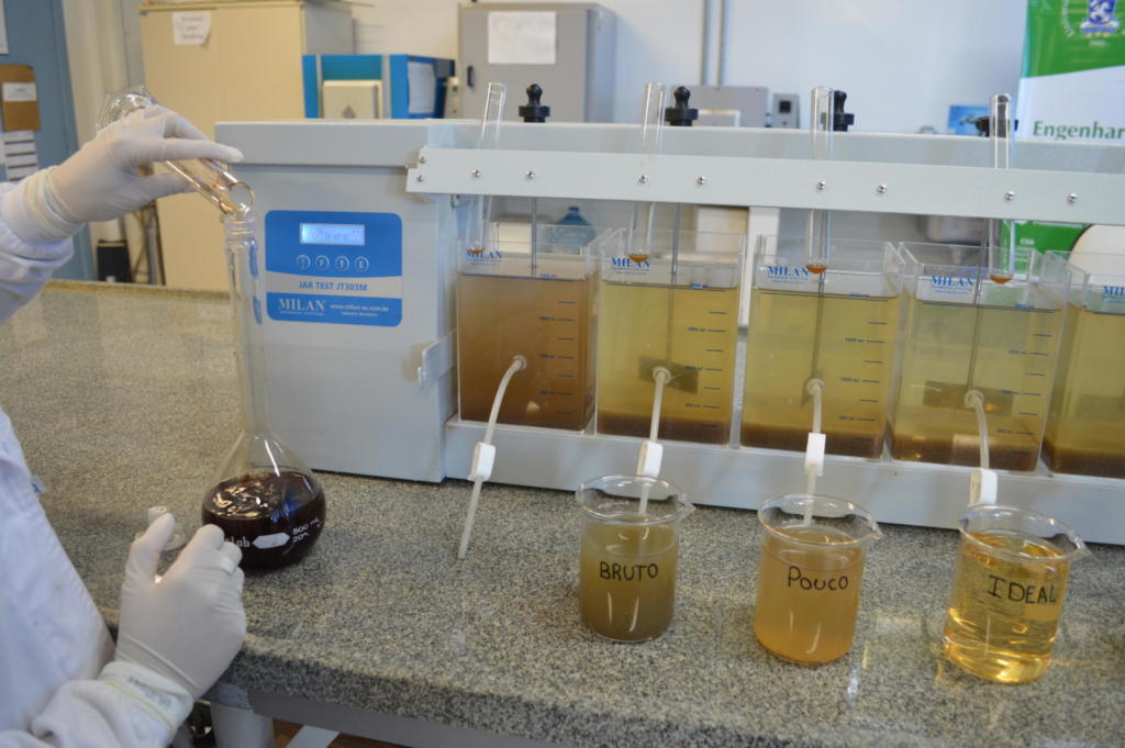 Três recipientes com água de diferentes cores em cima de uma bancada