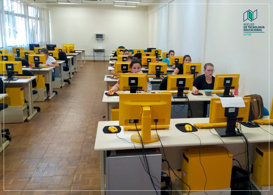 Foto de uma sala cheia de computadores amarelos, tem algumas pessoas na sala.