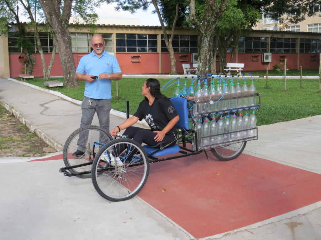 Aluna dirige carro movido a ar com garrafas pet e professor observa
