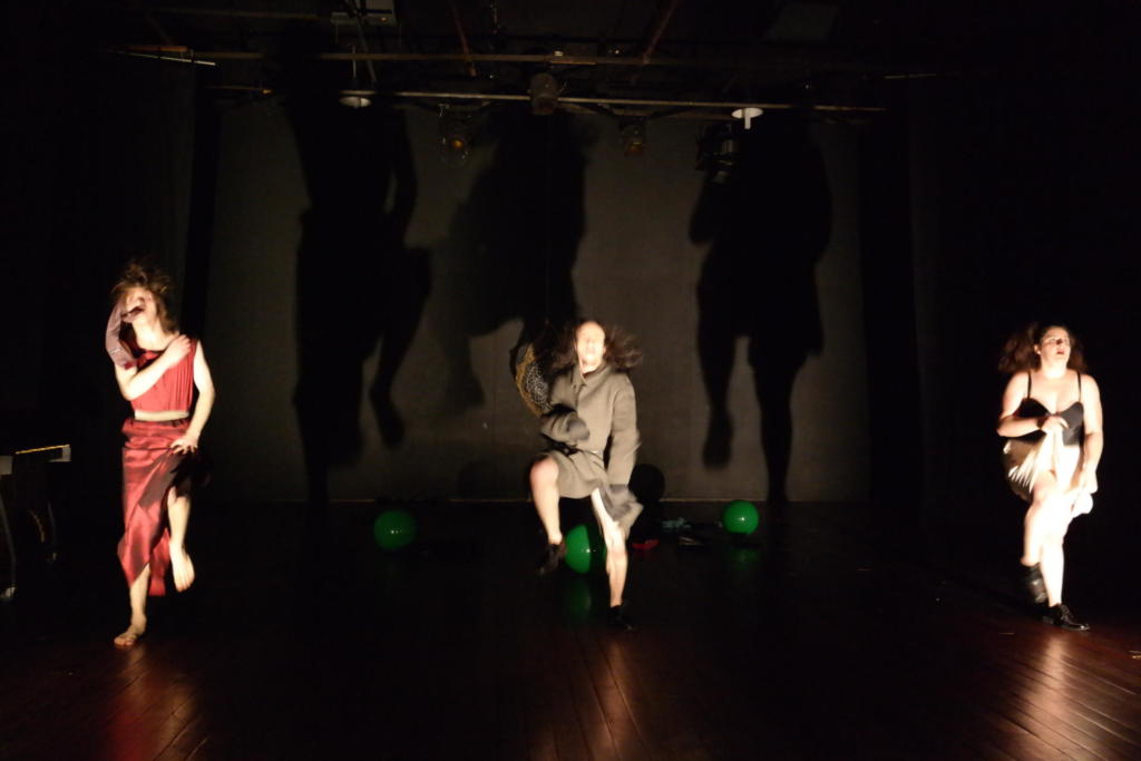 3 pessoas dançando em palco escuro com bolas verdes